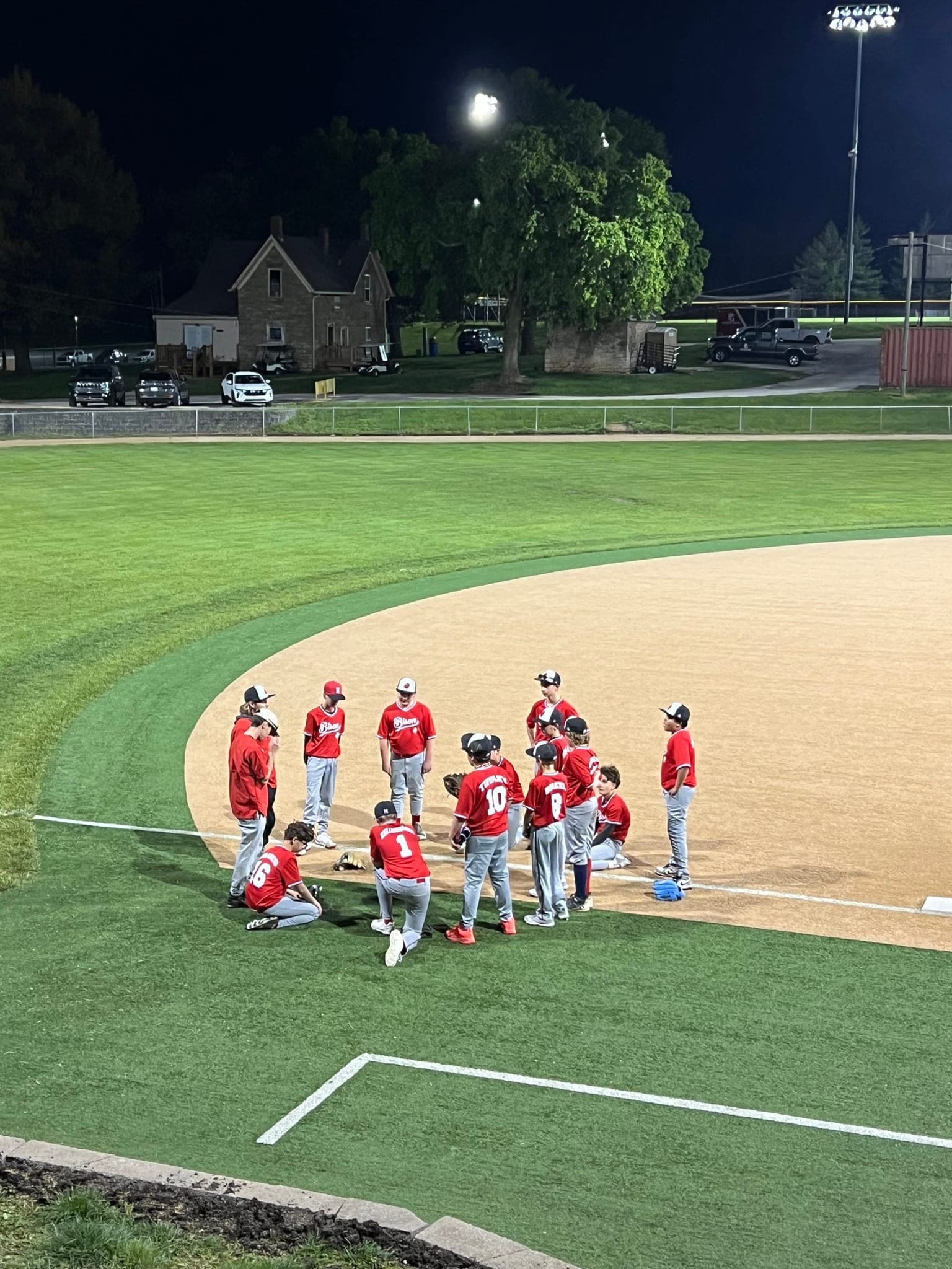 A youth baseball team gathered on the infield at night