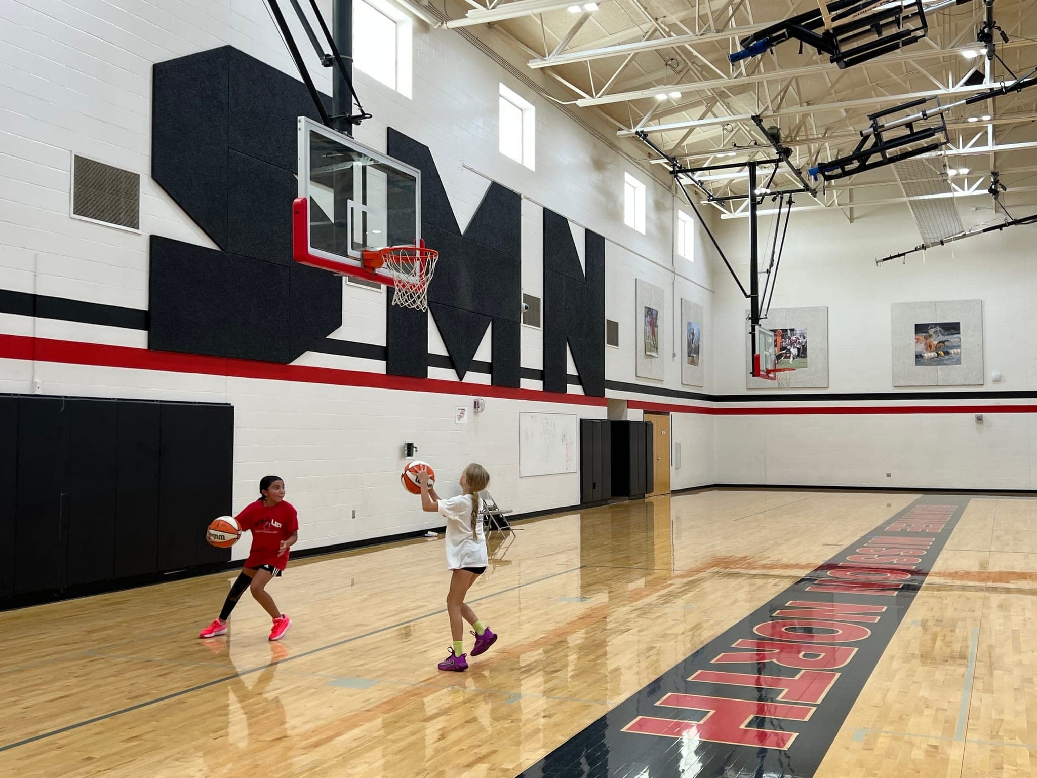 Two girls playing basketball in the gym